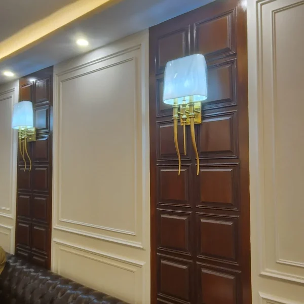 French wall moulding with wooden feature panels and decorative lighting at Custom House Karachi