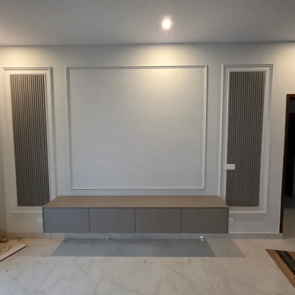 WPC wall paneling with custom media console and decorative moulding in DHA Karachi by Identity Interior